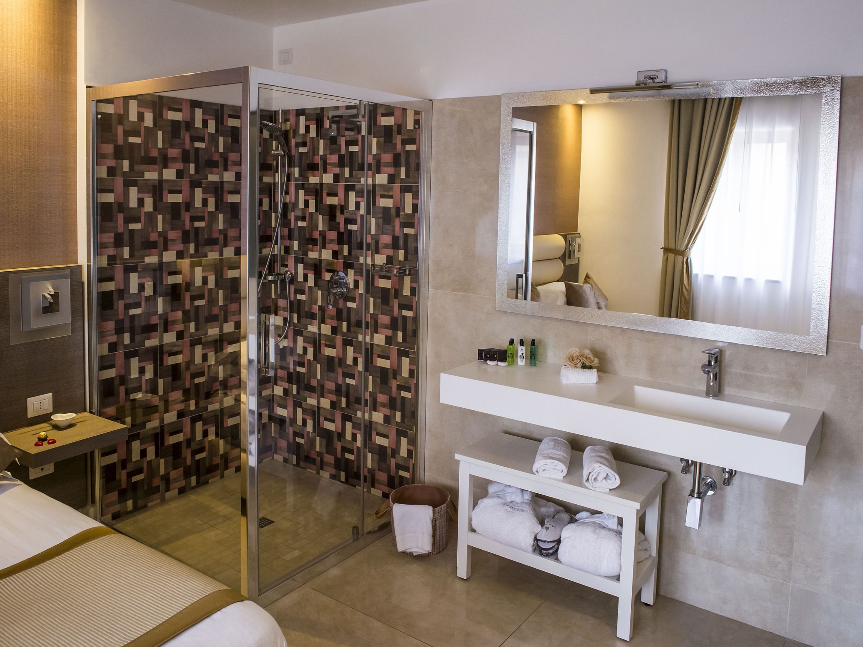A modern bathroom with a glass-enclosed shower, a white vanity with a mirror, and a towel rack.