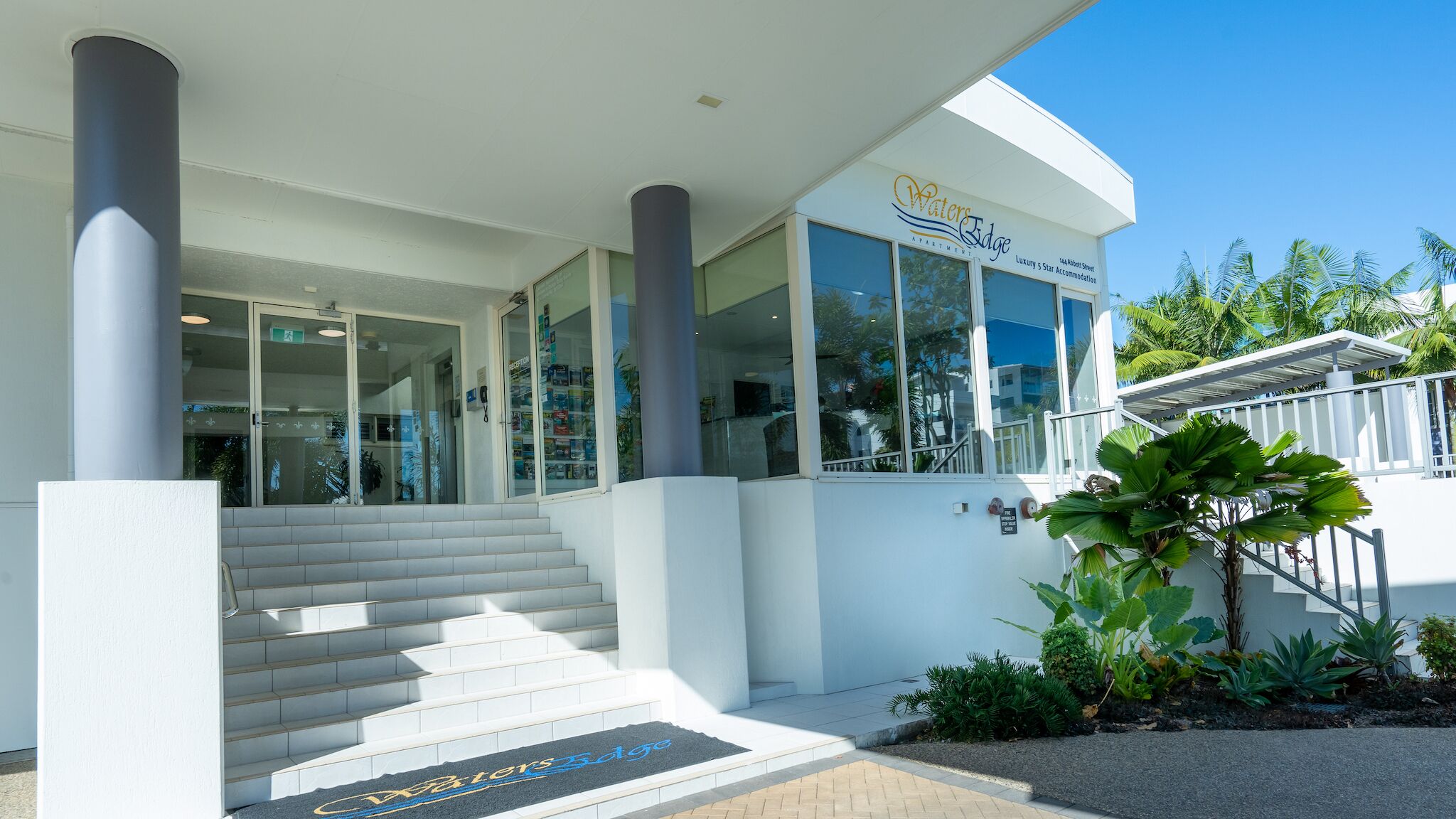 A modern building with a sign reading "Waters Edge Luxury 5 Star Accommodation" at the entrance.