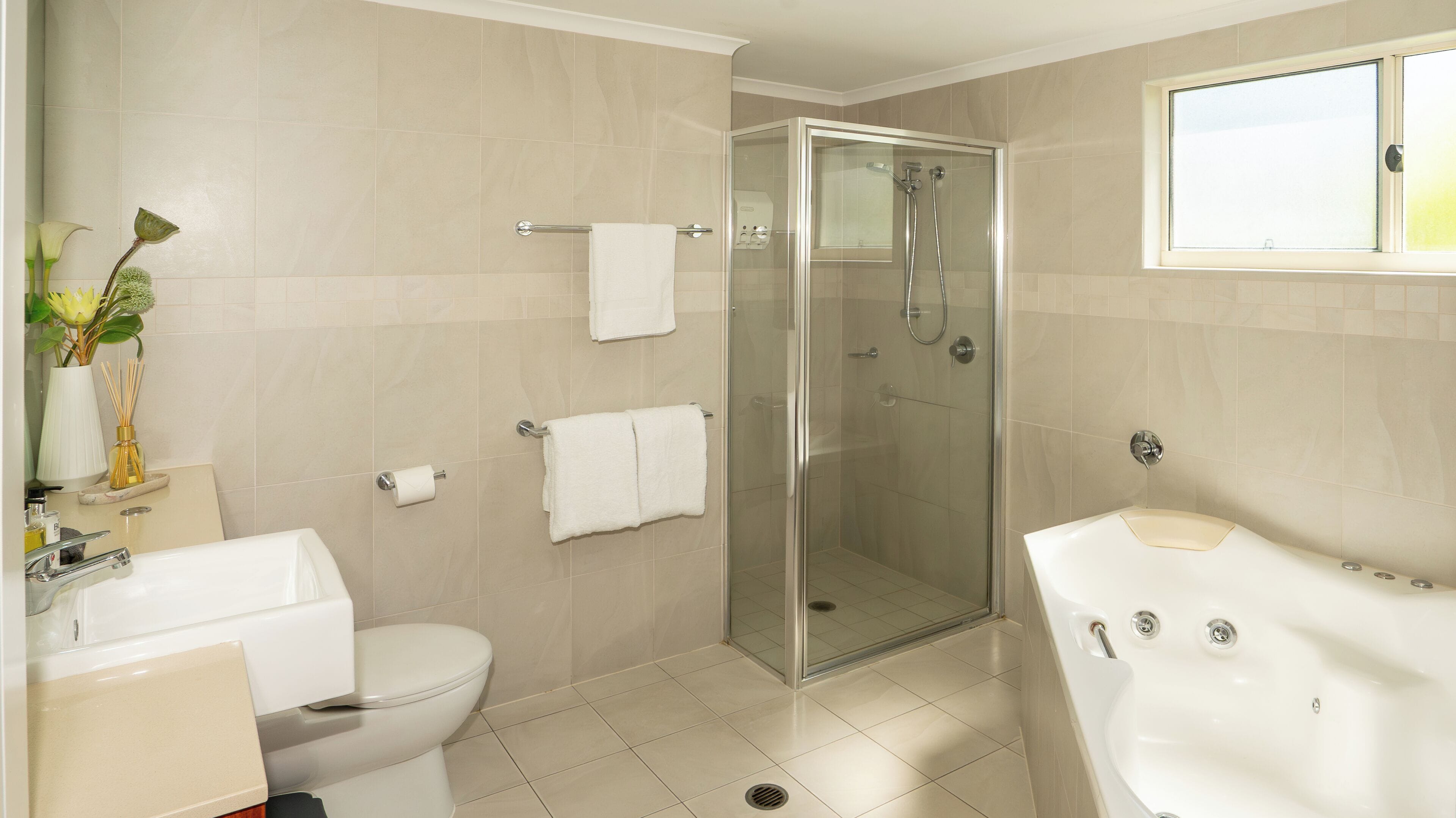 Ein modernes Badezimmer mit einer Duschkabine, einer weißen Toilette und einer großen Badewanne.