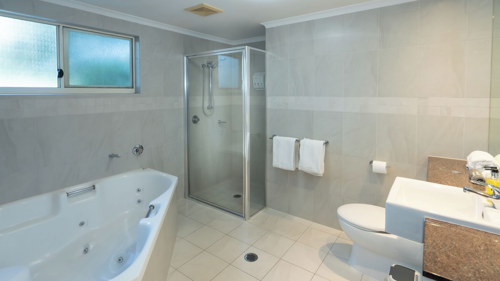 Un bagno moderno con doccia vetro, vasca freestanding e servizi igienici.