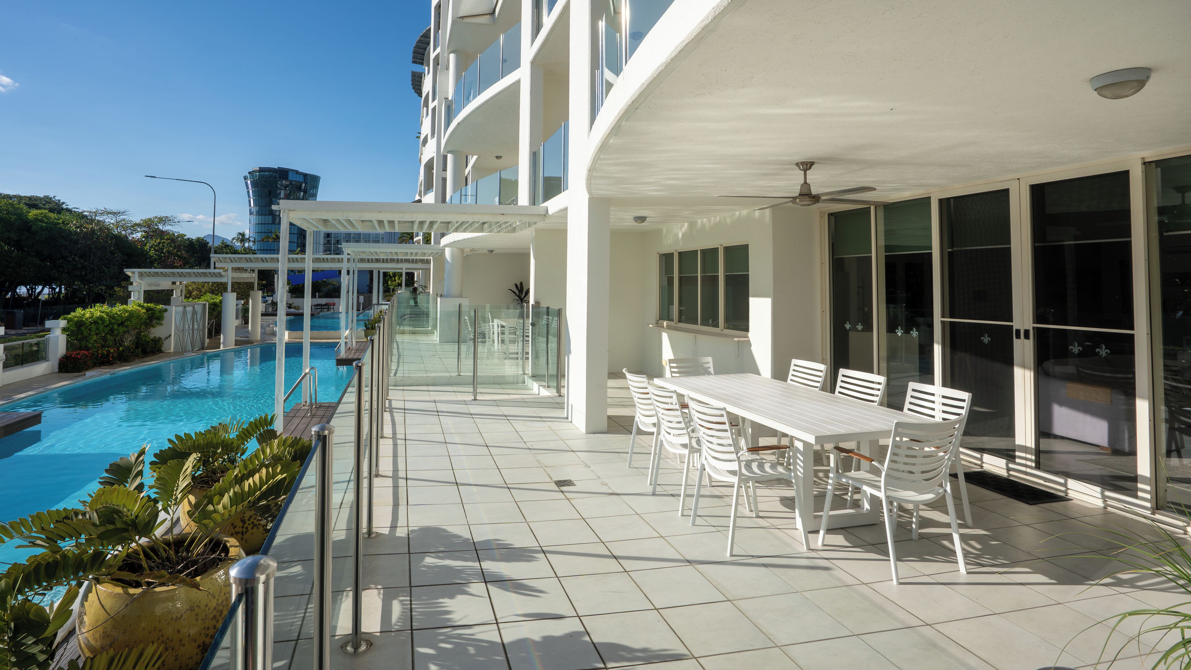 Ein modernes Hotel mit Pool, Sitzgelegenheiten im Freien und einer überdachten Terrasse.