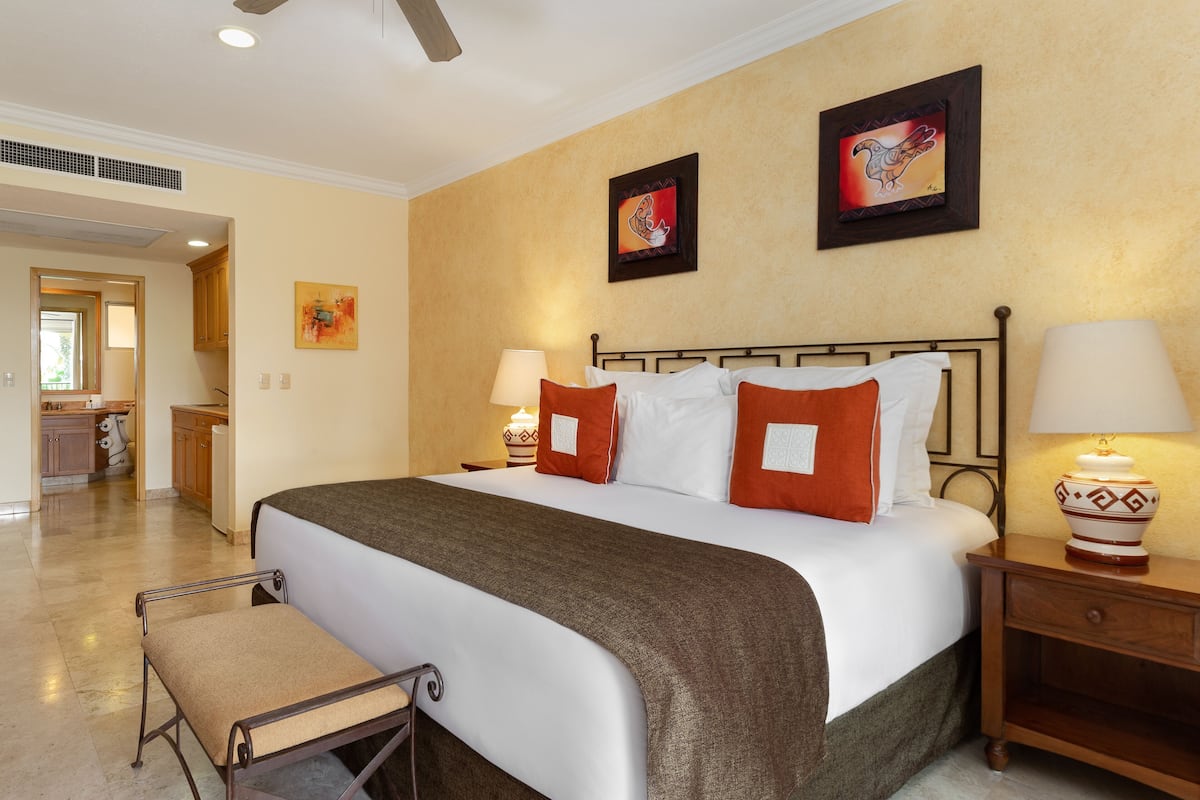 Una habitación de hotel con cama, mesitas de noche, una silla y obras de arte en las paredes.