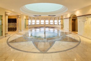A spacious atrium with a central circular water feature, large windows, and a high ceiling.