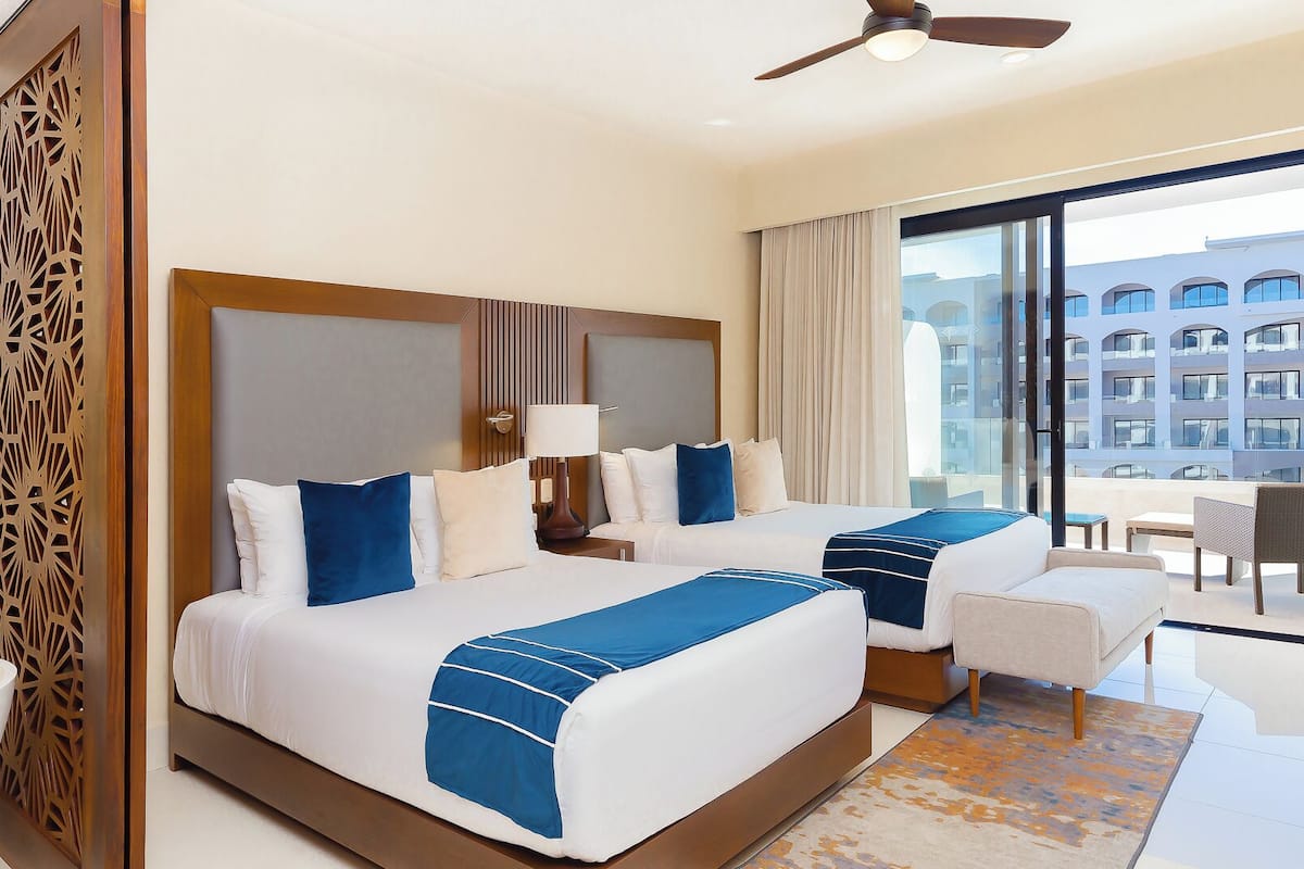 Habitación de hotel con dos camas, un balcón y vista a la ciudad, y diseño moderno.