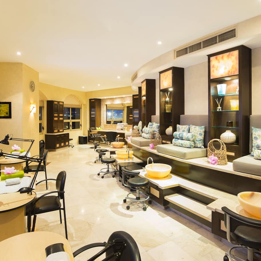A well-lit, modern spa room with a reception desk, seating area, and multiple sinks.