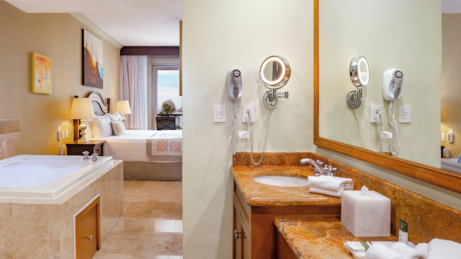 A hotel room with a large bed, a bathroom with a marble sink, and a view of the sea.