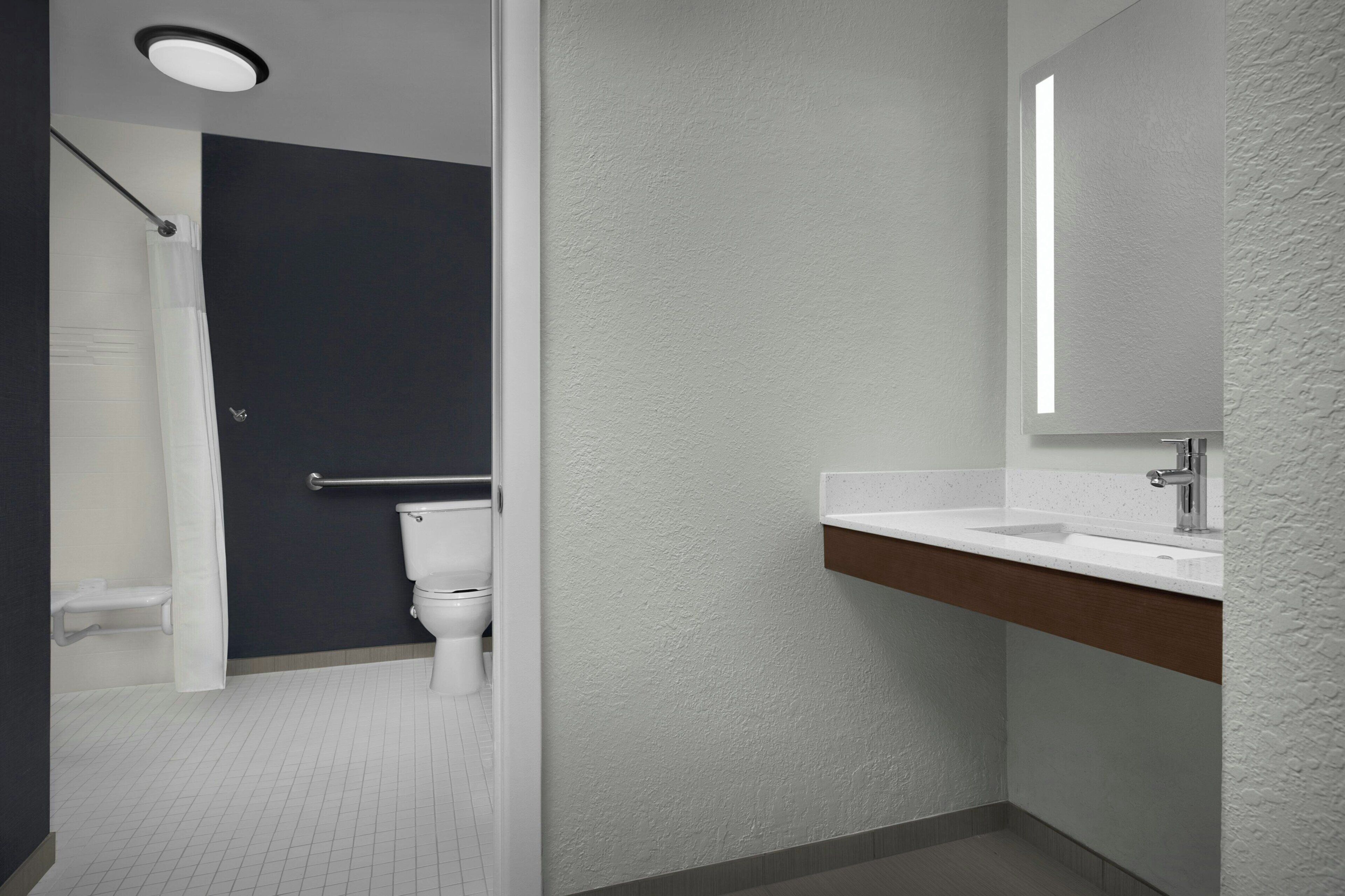 A modern bathroom with a white sink, a mirror, and a shower area.