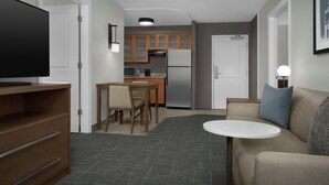 Un espace de vie compact comprenant un coin cuisine, un coin repas, un canapé et un téléviseur.