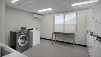 A laundry room with a washing machine, dryer, and stacked cabinets.