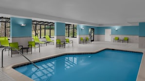 A swimming pool area with green chairs and a tiled floor.