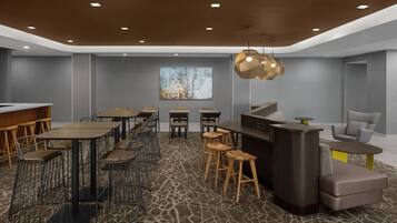 A modern bar area with a counter, stools, and tables.