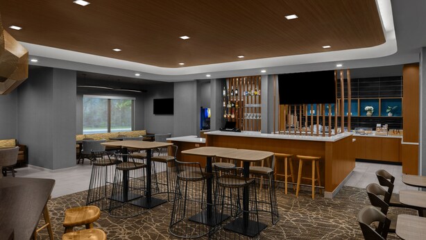 A modern bar area with seating, a counter, and a large window.