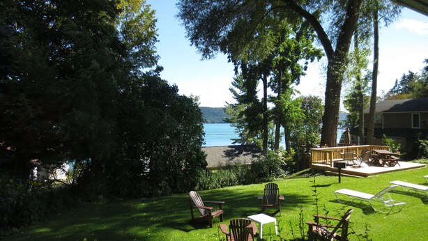 Ein Garten mit einer Terrasse, Gartenmöbeln und Blick aufs Wasser.