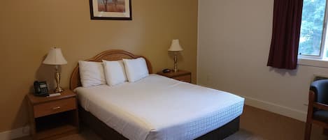 A hotel room with a bed, two bedside tables with lamps, a clock, a painting on the wall, and a window with curtains.