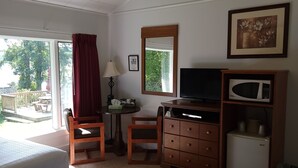 Ein Hotelzimmer mit einem Bett, einem Schreibtisch mit Computer, einem Fernseher, einer Mikrowelle und einem kleinen Kühlschrank. Ein Fenster bietet Blick ins Freie.