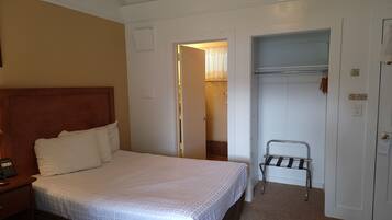 A hotel room with a bed, a nightstand, a closet, and a bathroom door.