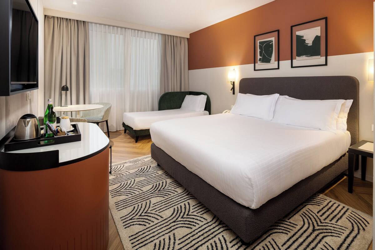Habitación de hotel con una cama grande, un escritorio con teléfono, una silla y un televisor.