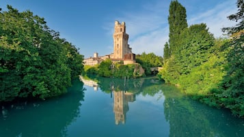 A historic tower surrounded by lush greenery and a calm river.
