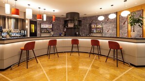 A bar area with a curved counter, multiple stools, and a variety of bottles and glasses on shelves. - Crowne Plaza Padova by IHG (Padova)
