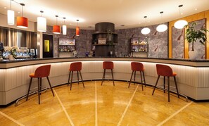 Una zona de bar con una barra curva, varios taburetes y una variedad de botellas y vasos en estantes.