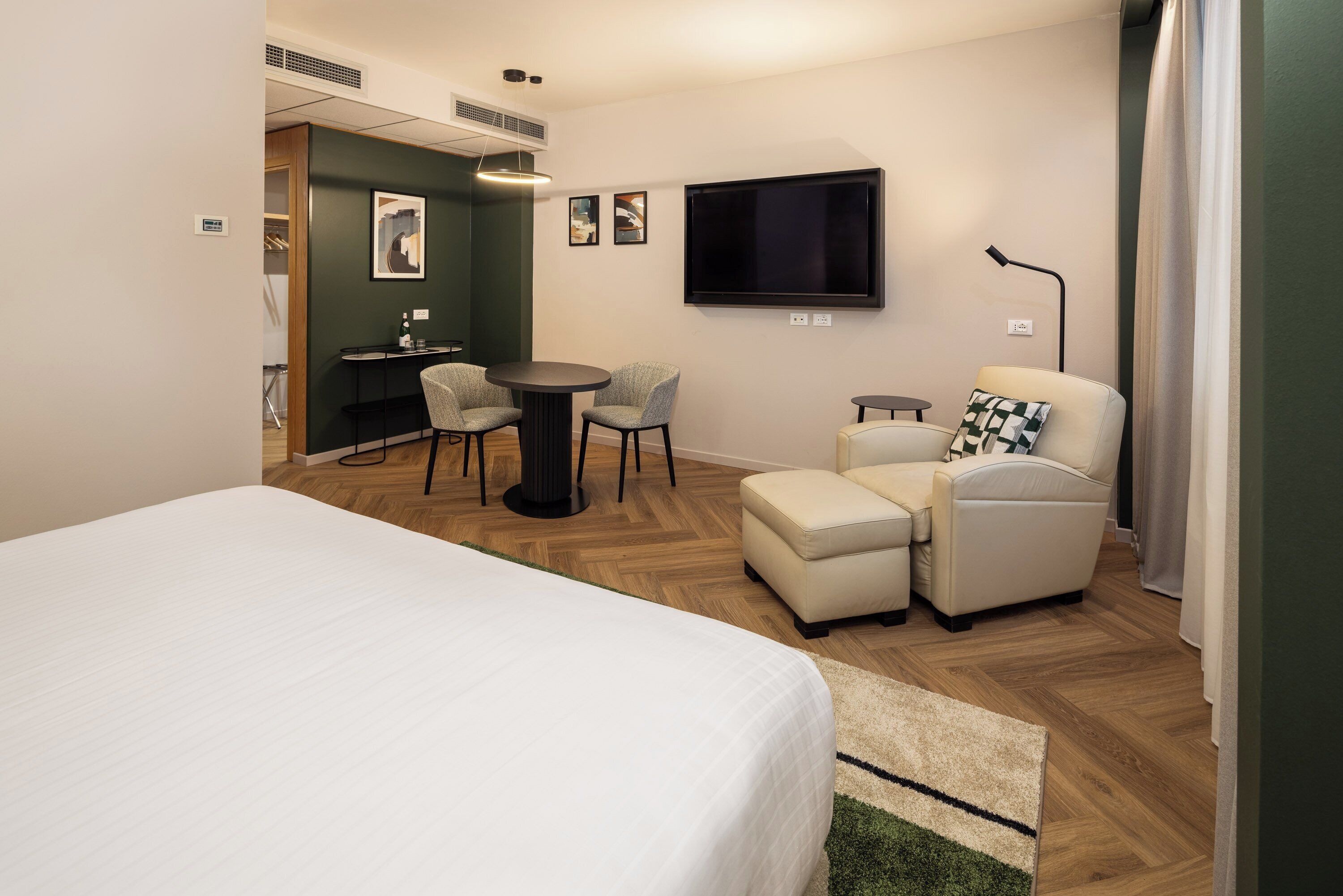 Une chambre d’hôtel comprenant un lit, un bureau avec deux chaises, une télévision et un canapé.