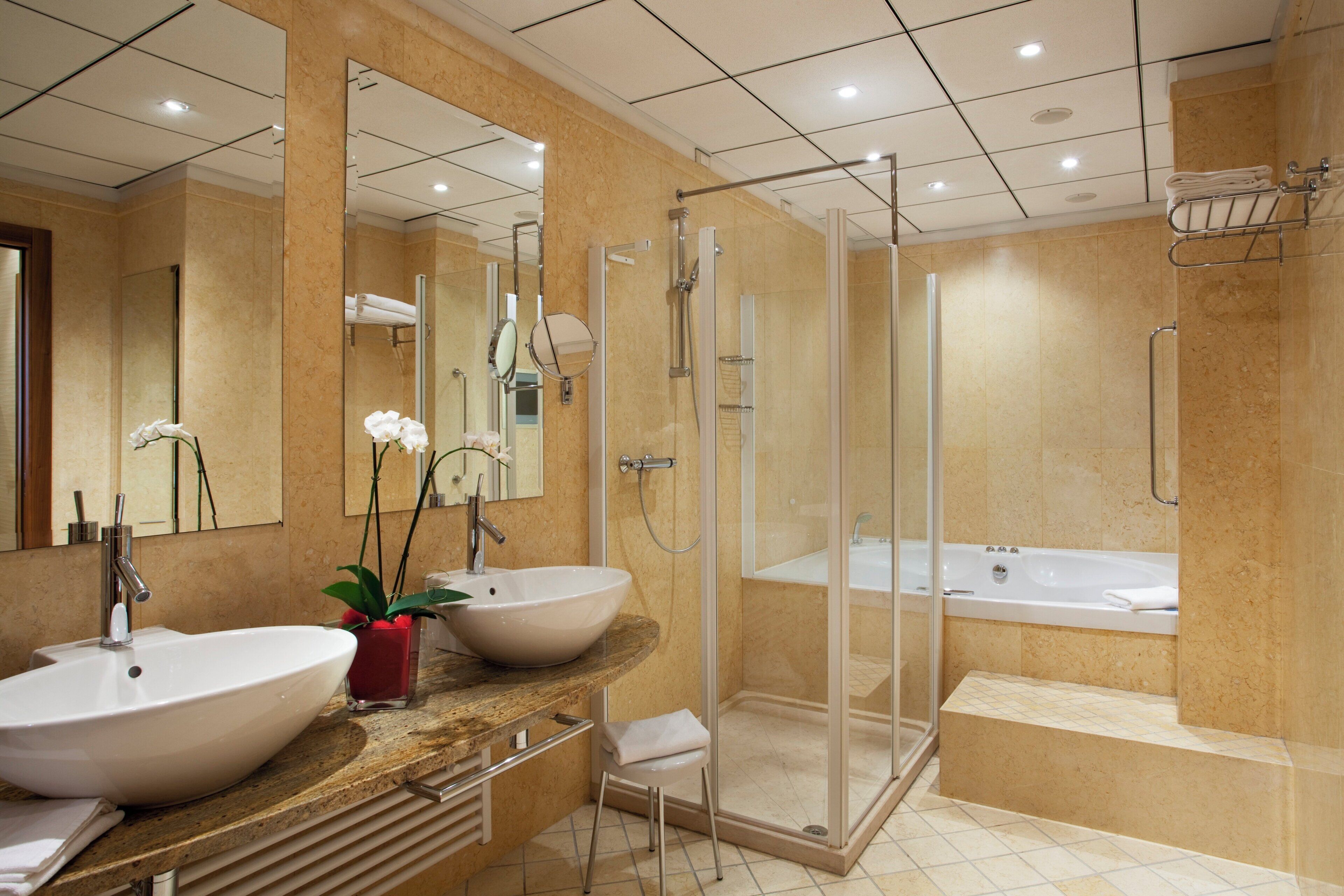 A modern bathroom with two large sinks, a glass-enclosed shower, and a separate bathtub.