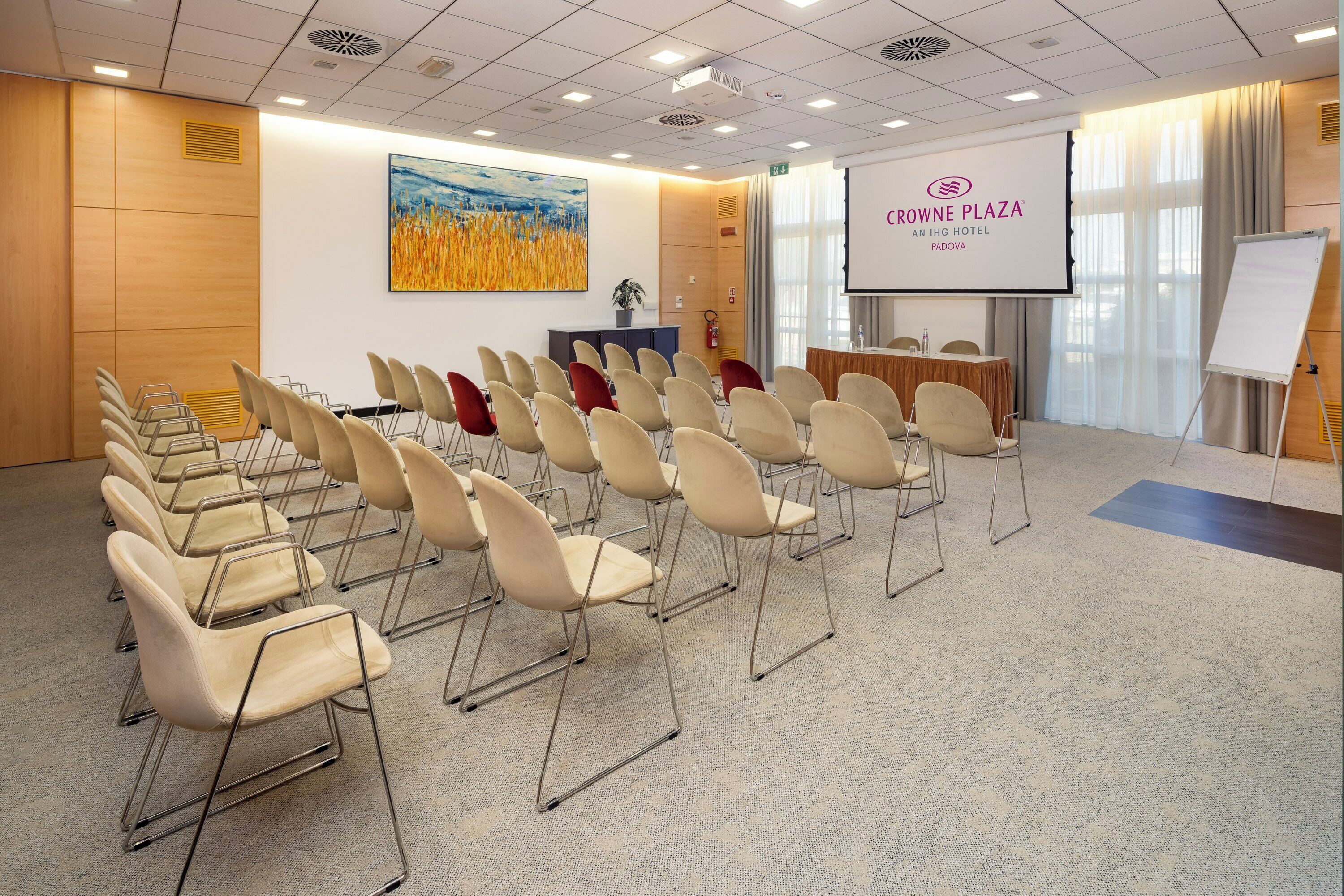 A conference room with rows of chairs, a projection screen, and a whiteboard.