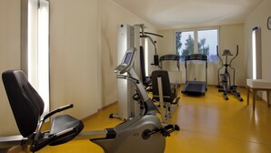 Un gimnasio con equipo de ejercicio variado, incluyendo una caminadora, una elíptica y máquinas de pesas.