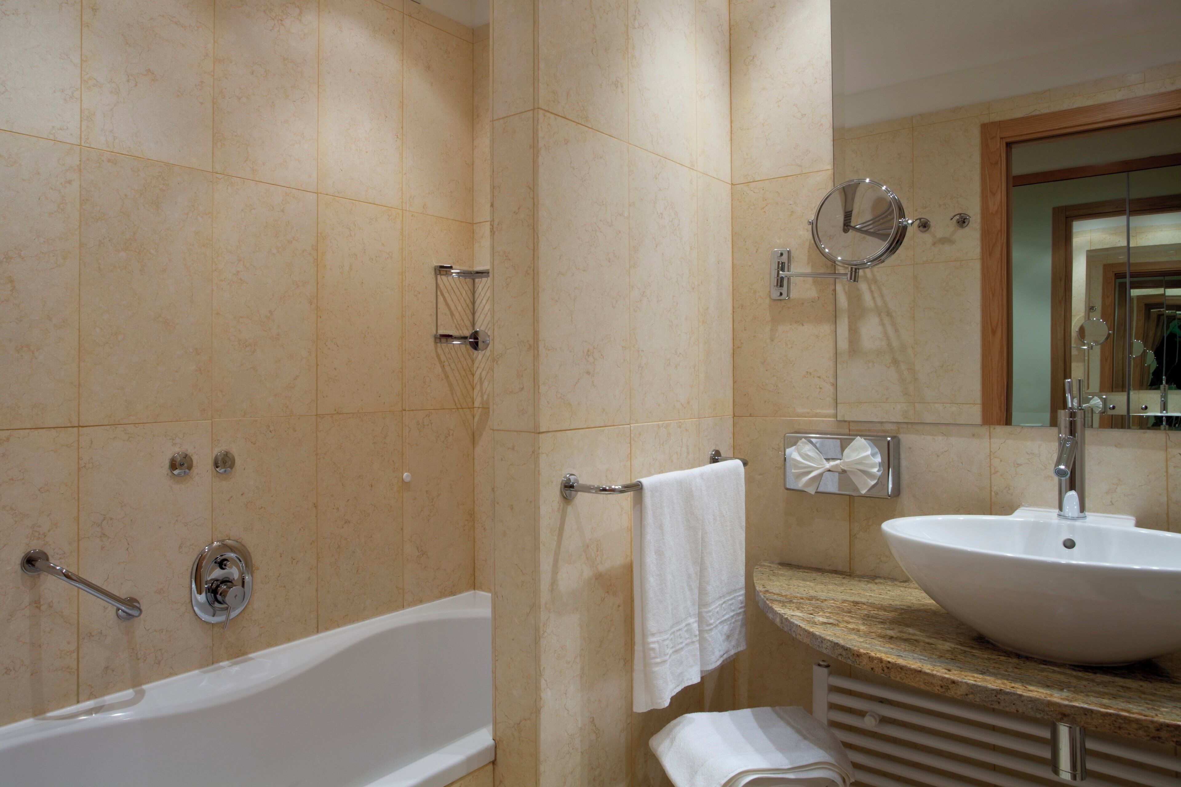 A bathroom with a bathtub, a sink, and a mirror.