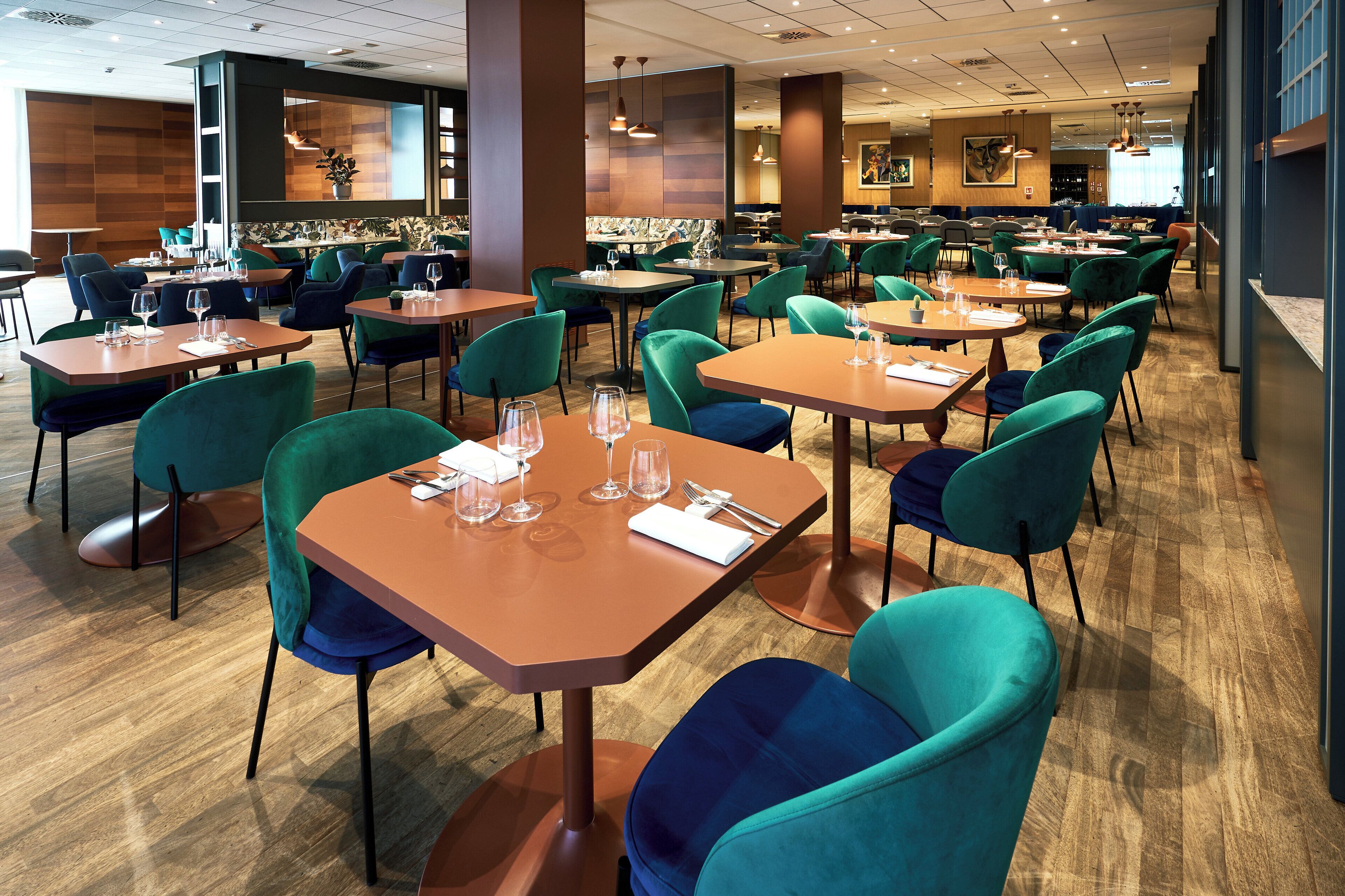 Un restaurante moderno con varias mesas y sillas, que ofrece una combinación de asientos de madera y tapizados.