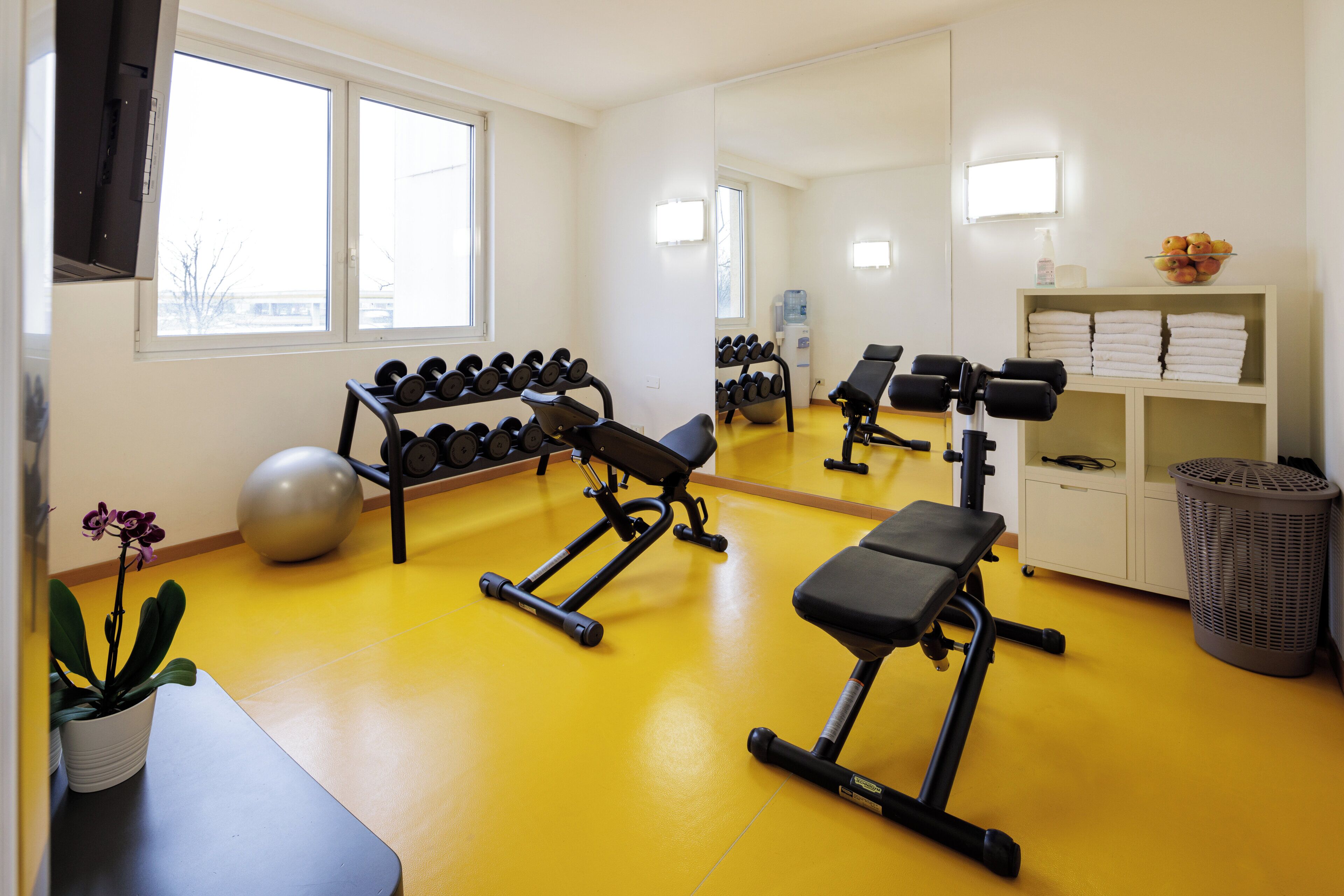 A gym with exercise equipment, a water dispenser, and a mirror.