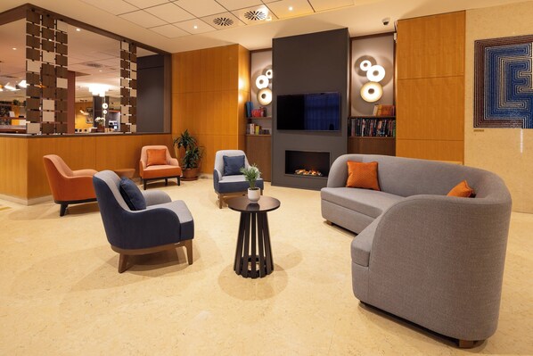 A modern lobby with seating, a fireplace, and a TV. - Crowne Plaza Padova by IHG (Padova)