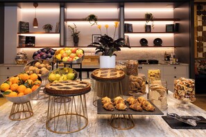 Una mesa de buffet con diferentes alimentos y una cocina moderna al fondo.