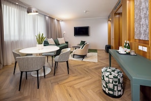 A modern living room with a round dining table, two sofas, a television, and a coffee table. - Crowne Plaza Padova by IHG (Padova)