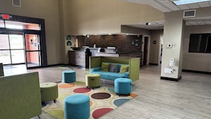 A lobby with a reception desk, seating area, and a patterned rug. - Wingate by Wyndham Warner Robins (Warner Robins)