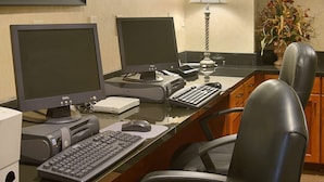 A hotel office with two monitors, a desk, a keyboard, a mouse, a lamp, and a chair. - Wingate by Wyndham Warner Robins (Warner Robins)