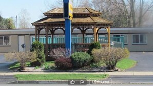 A gazebo with a wooden structure and a blue pole in the center.