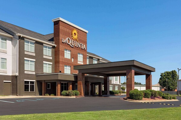 Un hotel La Quinta con fachada de ladrillo, entrada cubierta y estacionamiento.