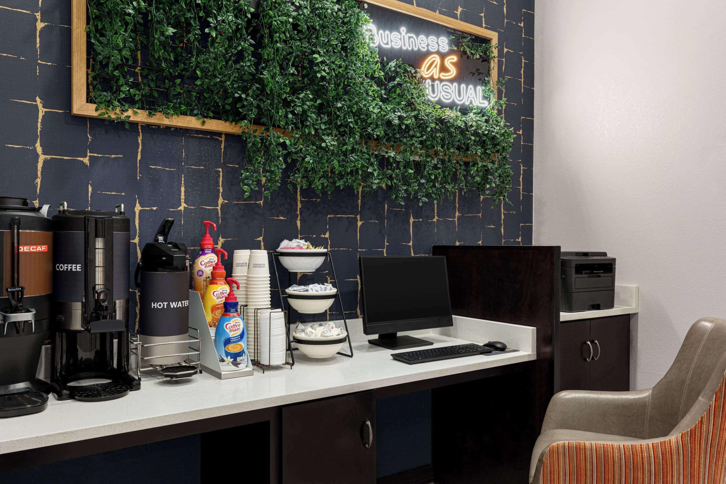 Un espacio de oficina moderno con estación de café, una computadora y un escritorio.