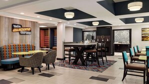 Un espace de restauration moderne offrant différents types de sièges, notamment des banquettes et des chaises individuelles, une table à manger centrale et un néon décoratif sur le mur.