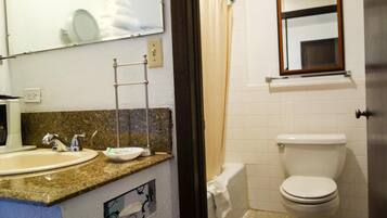 A bathroom with a sink, mirror, towel rack, toilet, and a shower curtain.