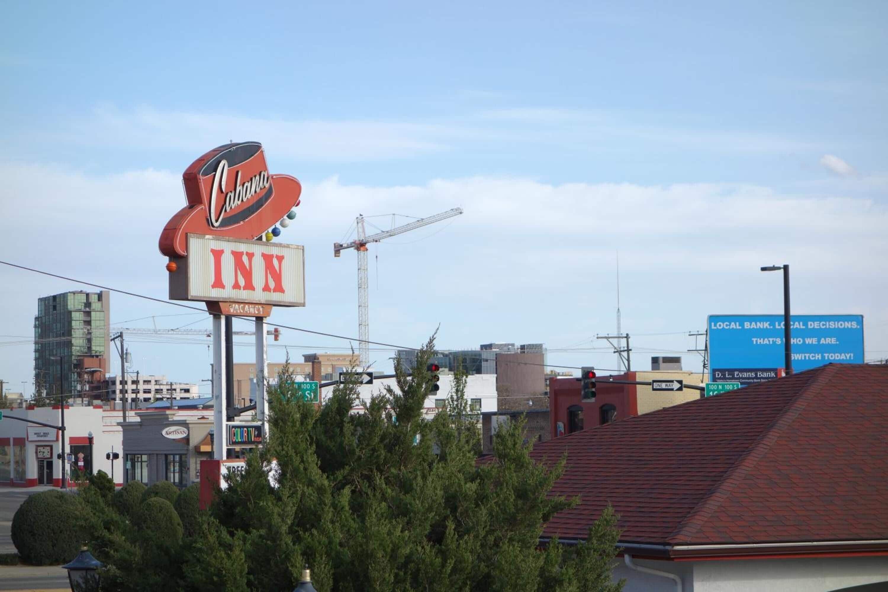 A sign for a Cabana Inn with a visible 'VACANCY' sign and a construction crane in the background.
