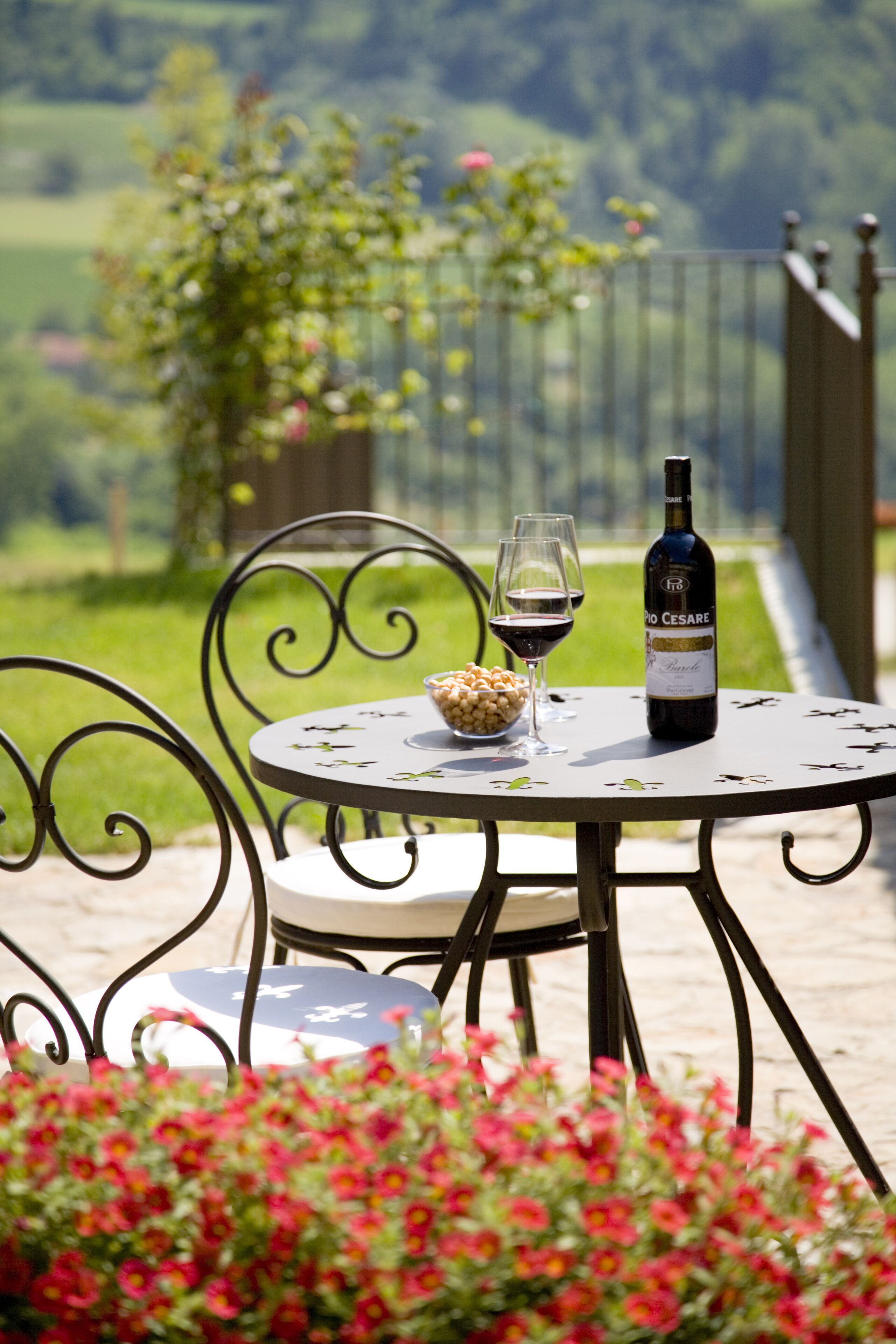 A round table with a bottle of wine, two glasses, and a bowl of snacks.