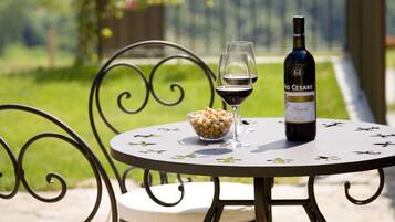 A round table with a bottle of wine, two glasses, and a bowl of snacks.