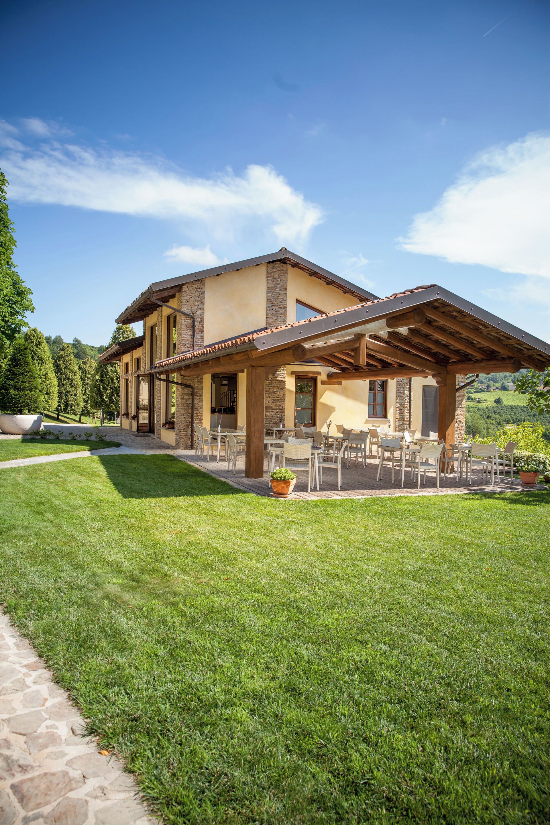 A two-story house with a patio area featuring outdoor furniture.