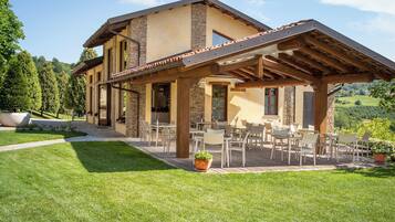 A two-story house with a patio area featuring outdoor furniture.