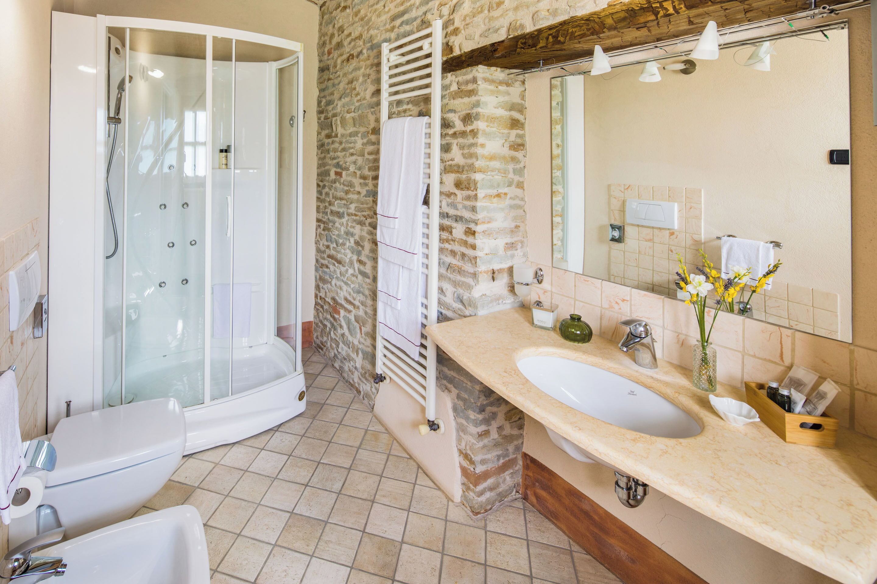 A bathroom with a glass-enclosed shower, a double sink vanity, and a large mirror.