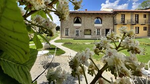A stone building with a courtyard, outdoor seating, and a clear sky. - Hotel Relais Montemarino (Borgomale)