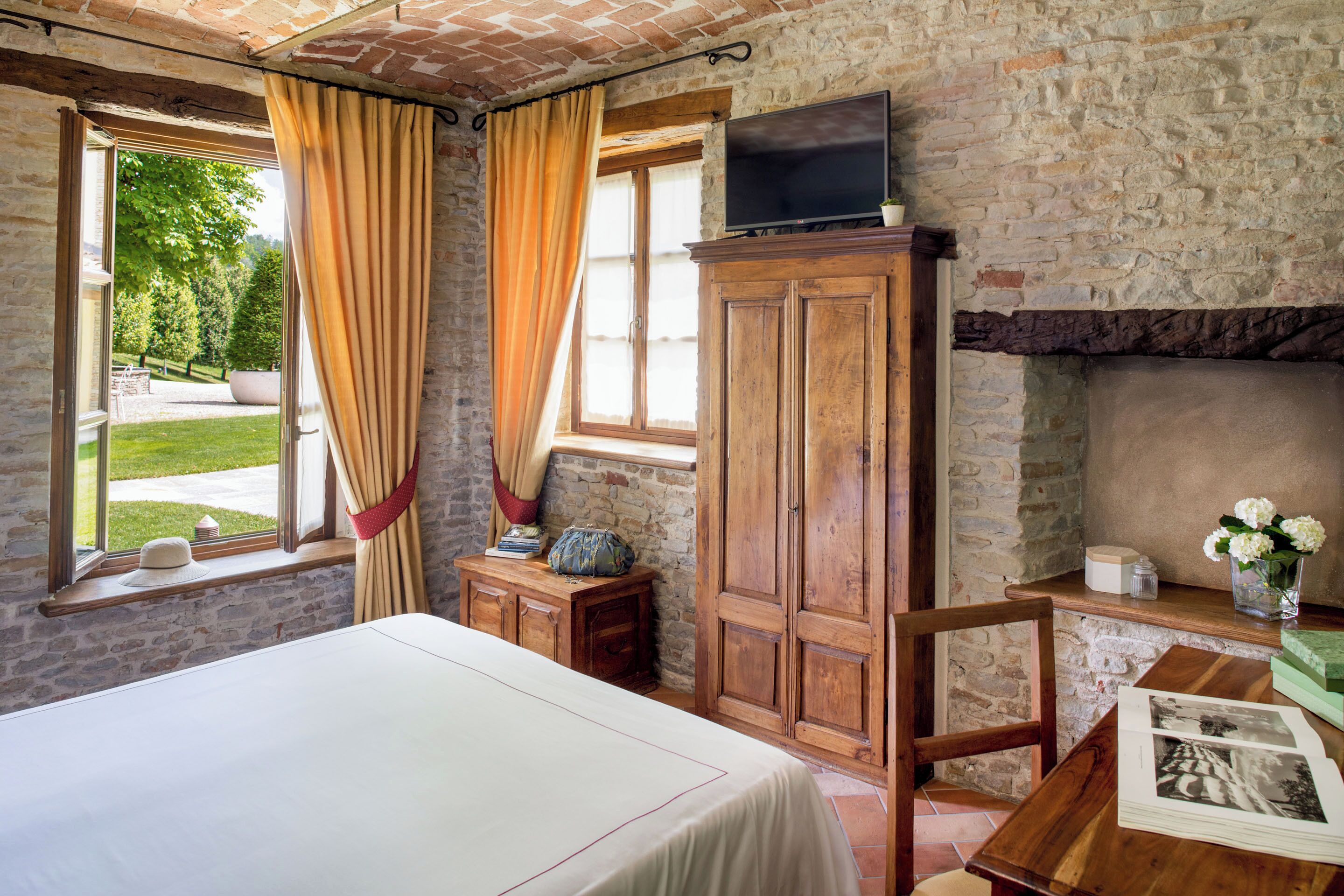 Un dormitorio con una cama, un armario de madera, un televisor y una chimenea.