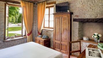 Un dormitorio con una cama, un armario de madera, un televisor y una chimenea.